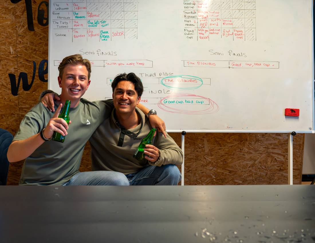 Two colleagues at the office beer-pong tournament board